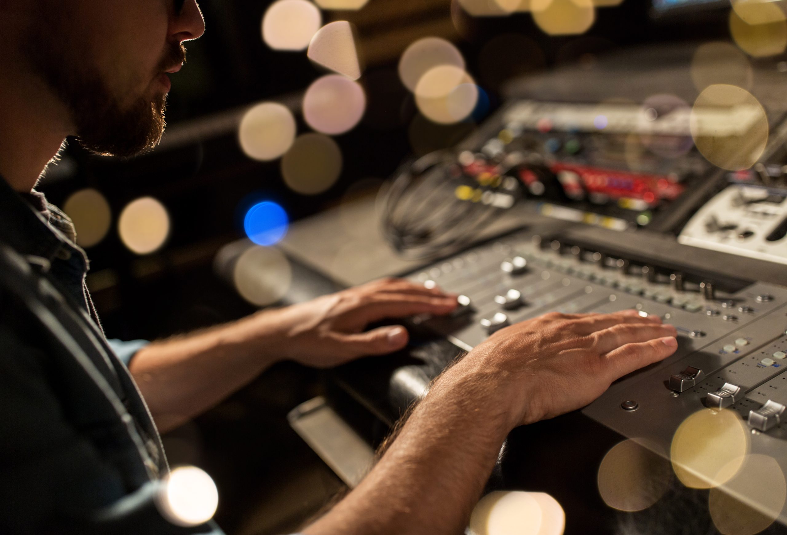 man using mixing console in music recording studio