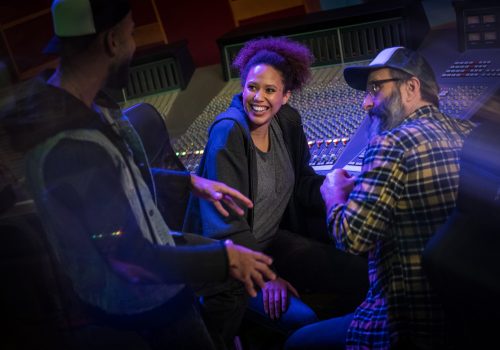 Male singer talking with female singer and composer in recording studio.